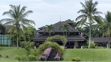 A two-story building with a covered entrance, surrounded by palm trees and a well-maintained lawn.