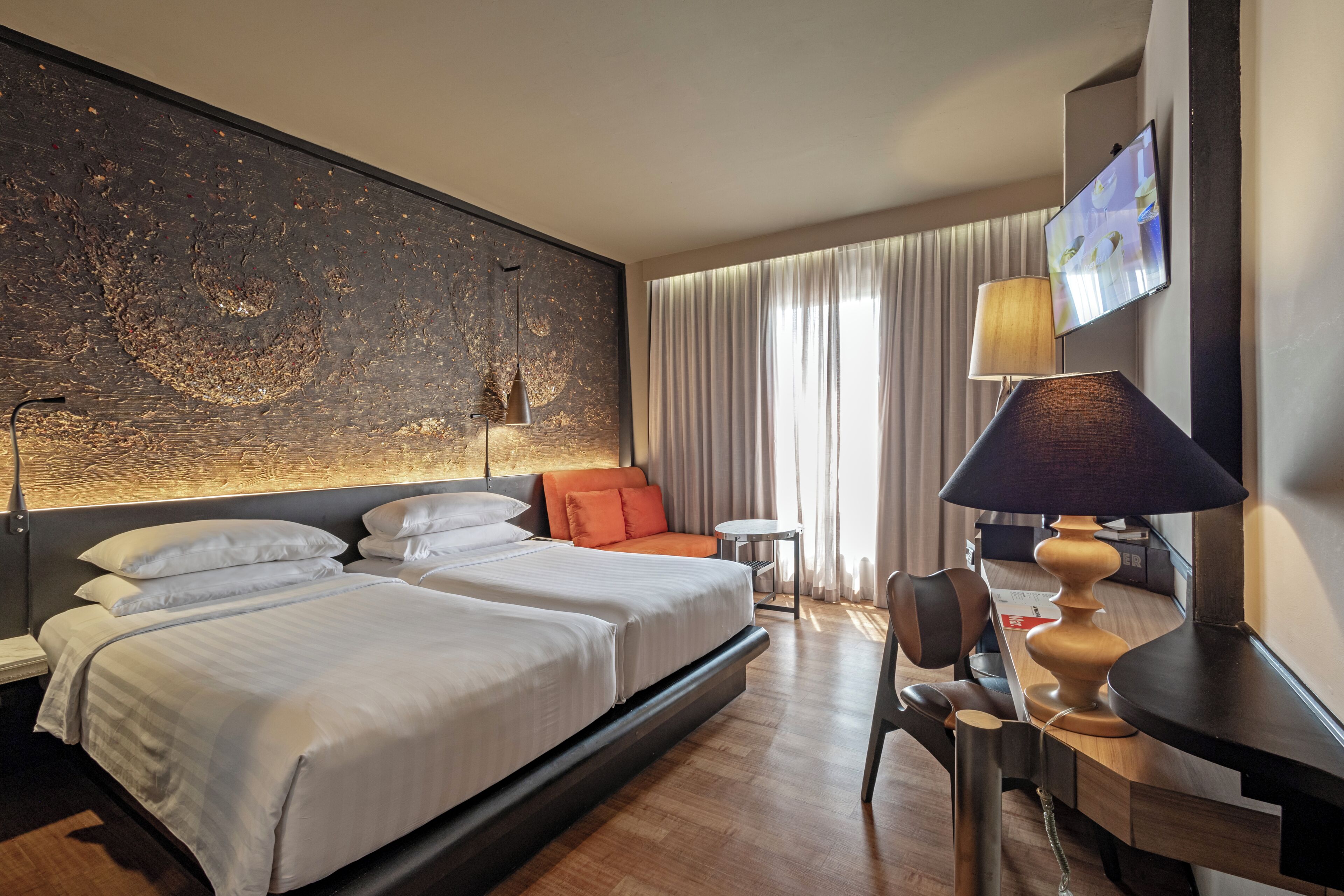 Une chambre d’hôtel avec un grand lit, un bureau, une chaise, une télévision et un tableau au mur.
