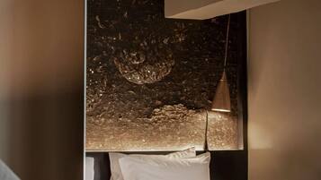 A modern hotel room with a bed, a desk, a chair, and a decorative wall.