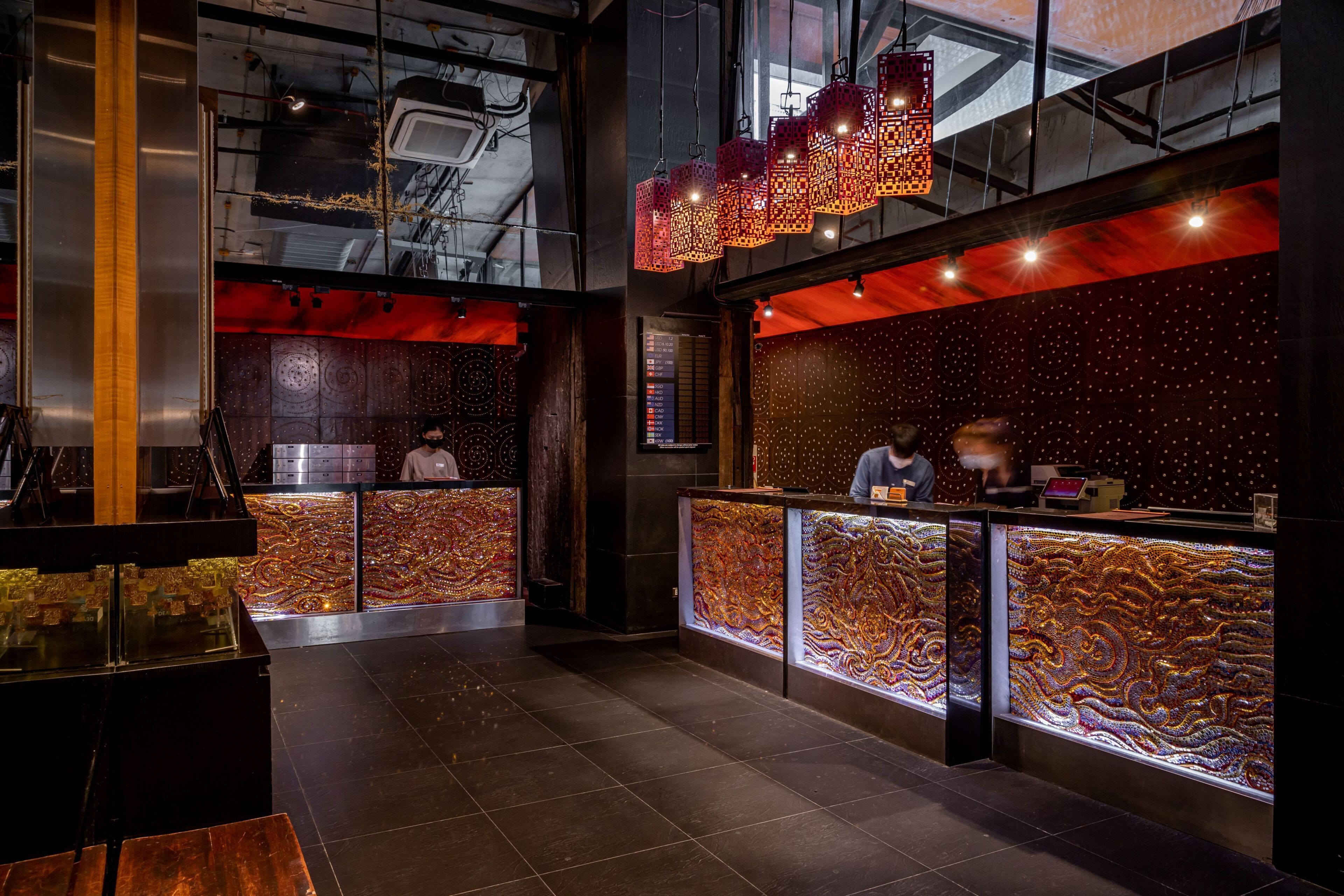 A modern interior with a reception desk, decorative wall panels, and hanging lanterns.