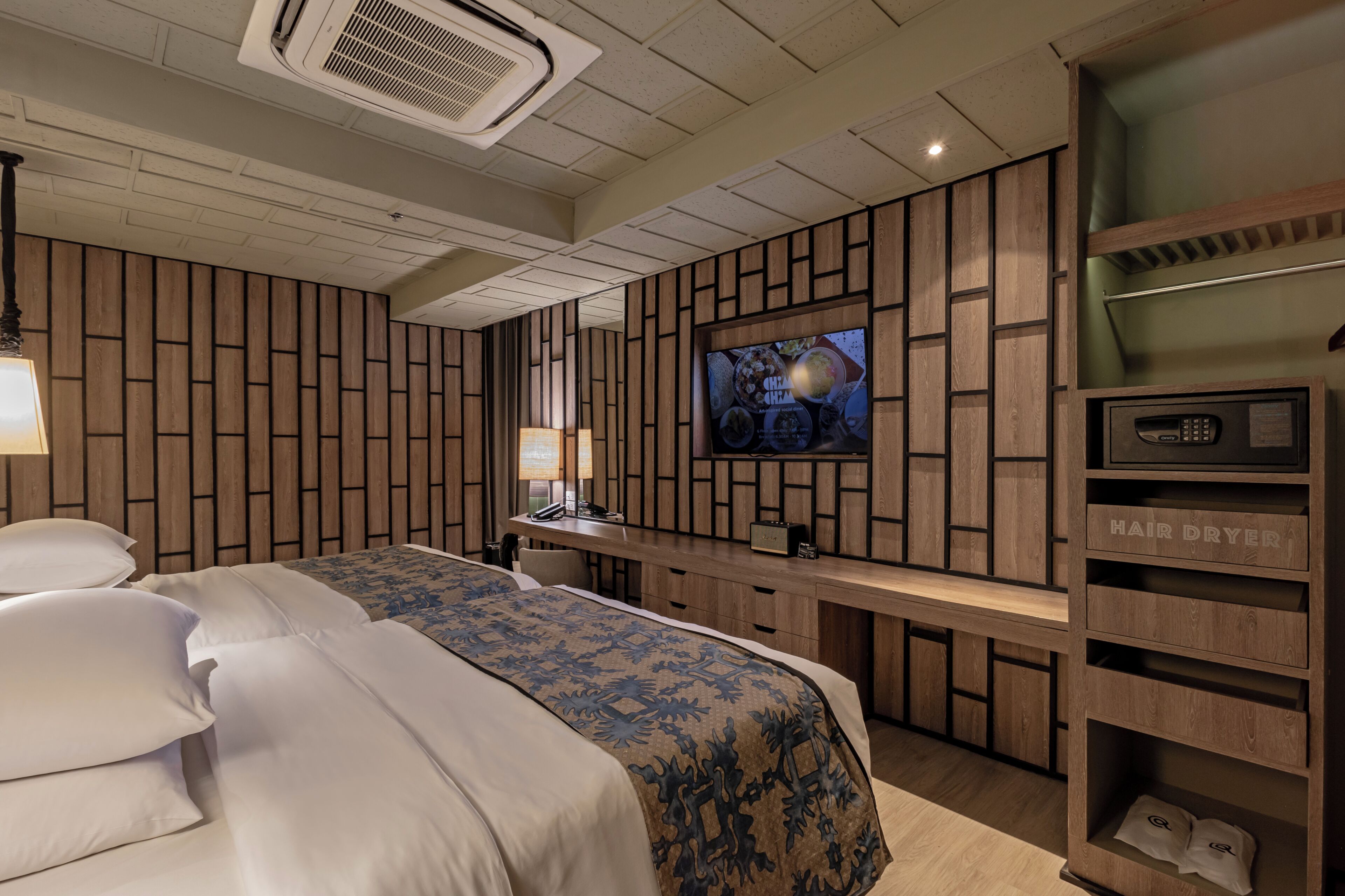 A hotel room with a large bed, a desk with a flat-screen TV, a hair dryer, and a built-in shelf.