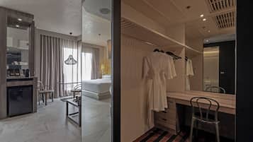 A modern hotel room with a bed, a desk, a chair, a mirror, and a wardrobe.