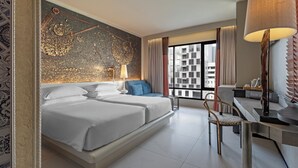 Una habitación de hotel moderna con una cama grande, un escritorio, una silla y vistas a la ciudad.