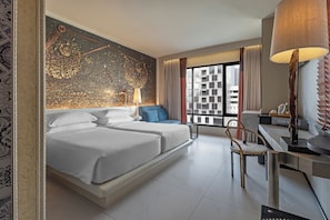 Quarto de hotel moderno com uma cama grande, uma escrivaninha, uma cadeira e vista para a cidade.