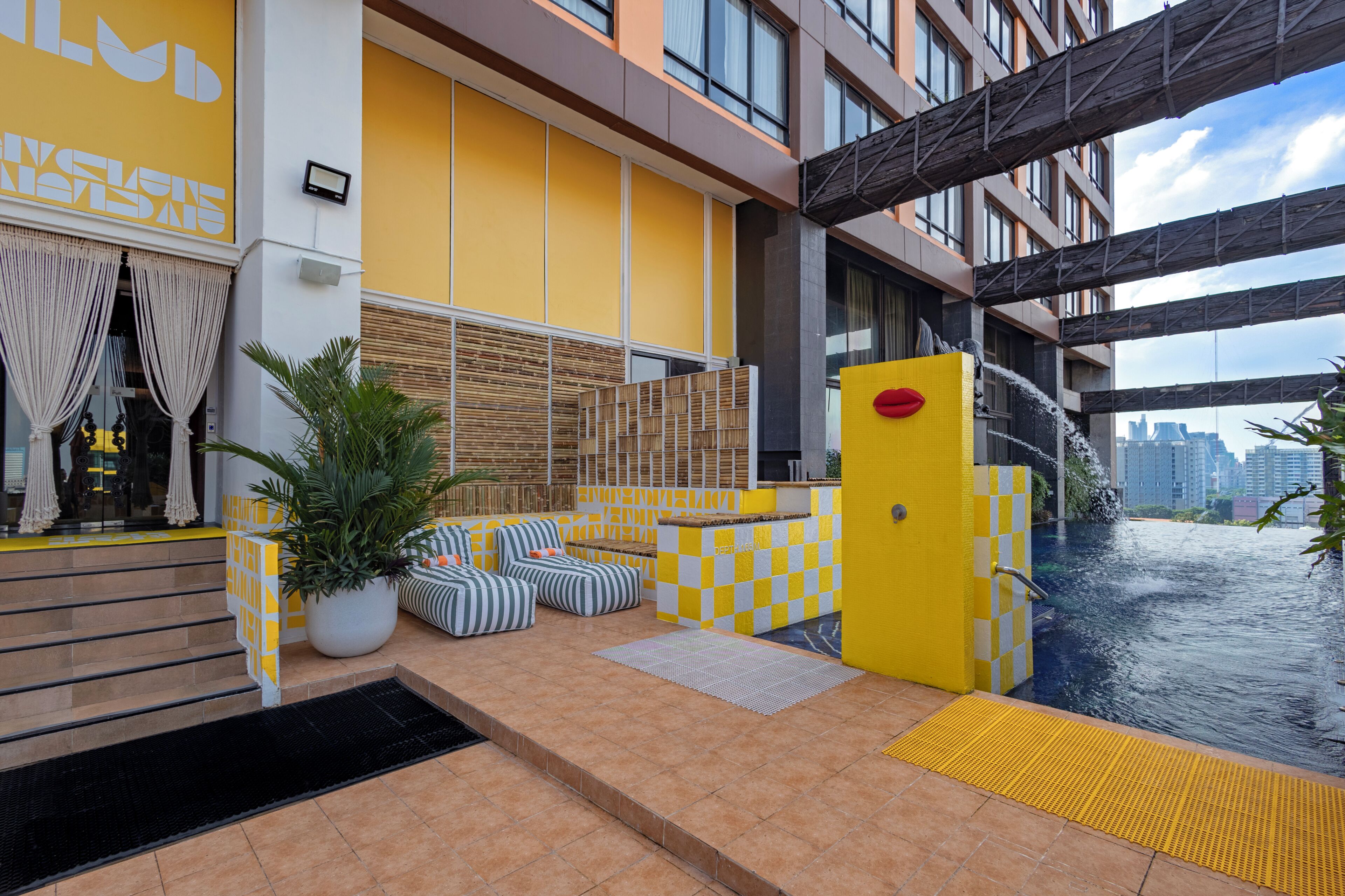 A hotel lobby with a checkered floor, a large potted plant, and a water feature.