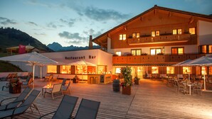 A restaurant bar with outdoor seating and a wooden deck. - Sporthotel Steffisalp (Warth)