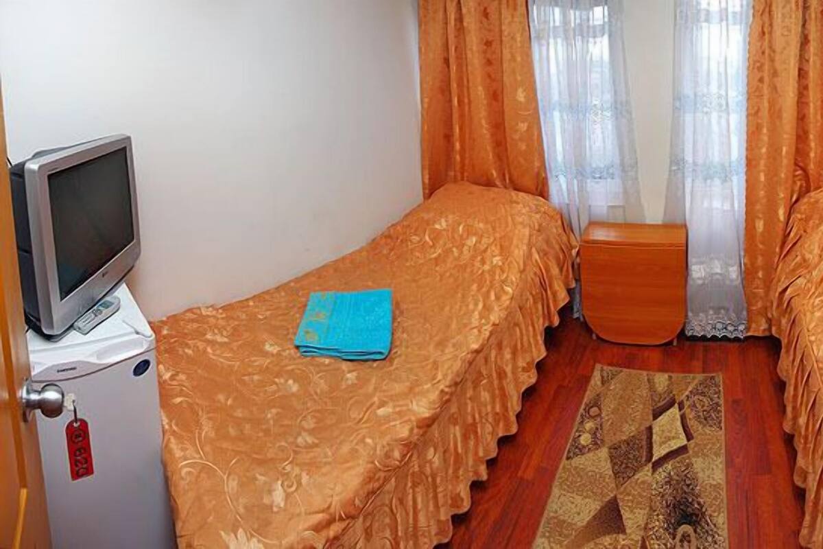 A small room with two beds, a TV, a wooden cabinet, and a bathroom.