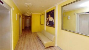 A hallway with yellow walls, a bench, and a chandelier. - Zirka Hotel (Odesa)