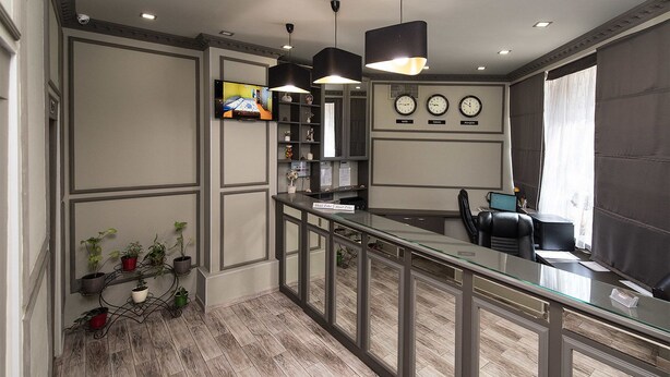A hotel reception area with a glass counter, black chairs, and a TV screen. - Zirka Hotel (Odesa)