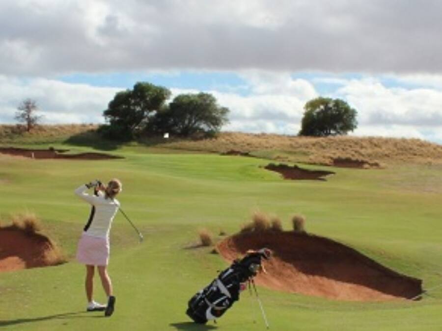 Un campo de golf con búnkeres y árboles al fondo.