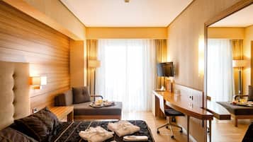 A hotel room with a large bed, a desk, a chair, and a mirror.