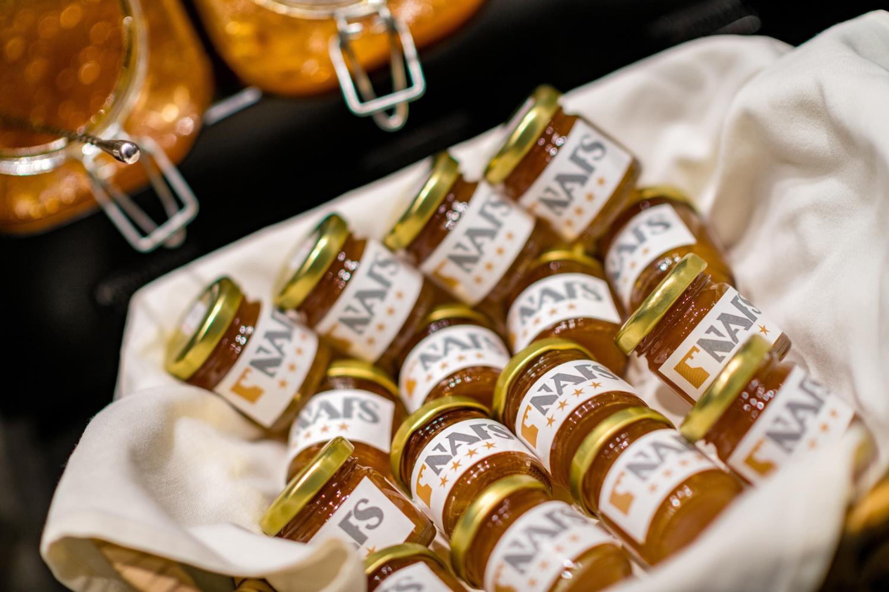 A tray of jars with labels, likely containing a food item, placed on a cloth.