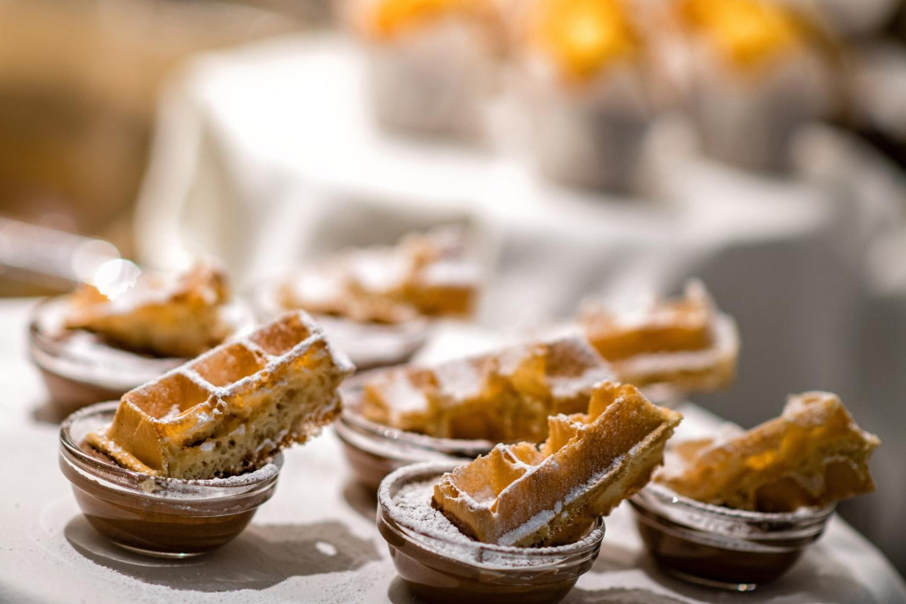 A close-up of waffles in small bowls with powdered sugar.