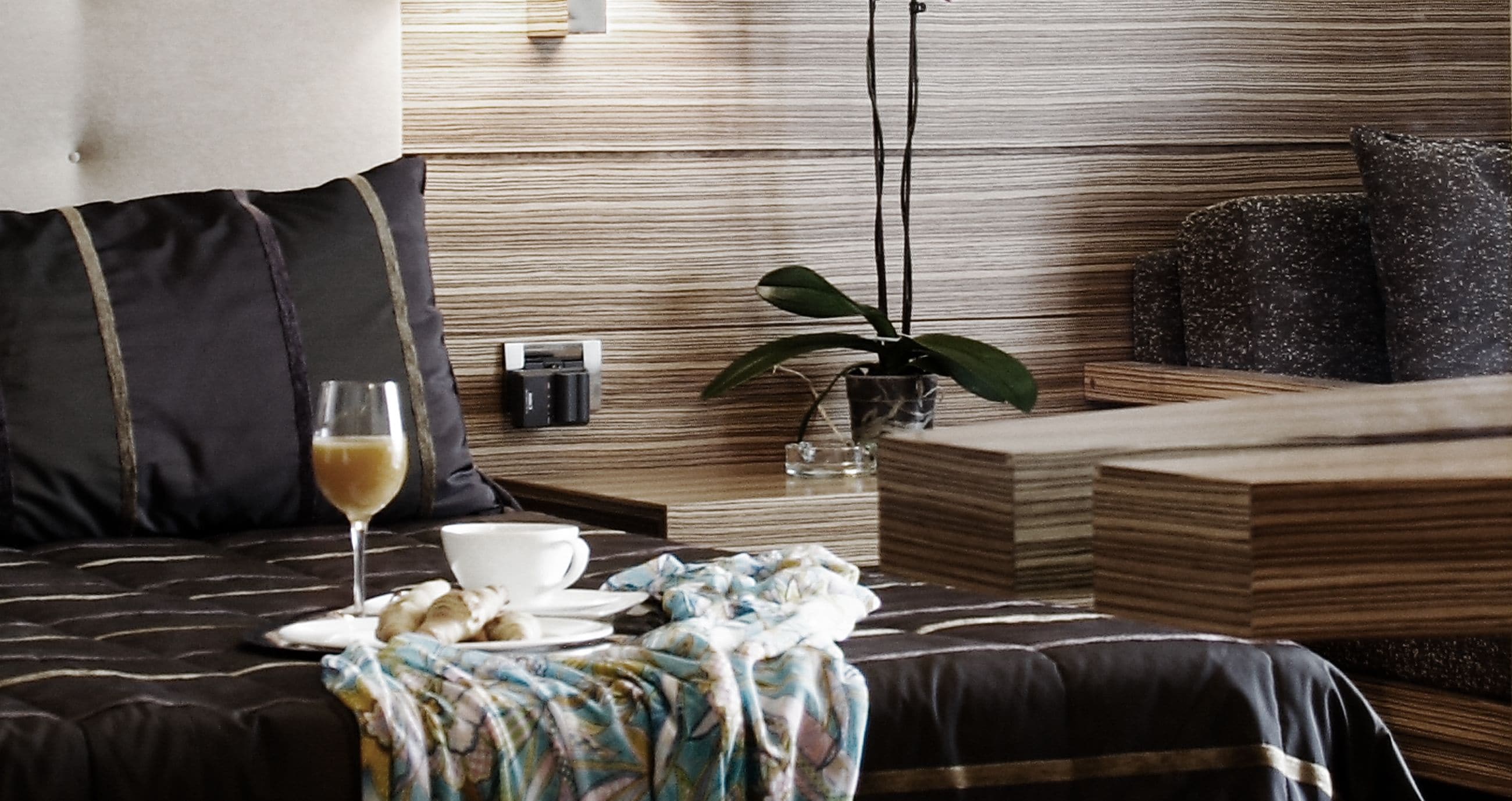 A neatly arranged bedroom with a bed, bedside table, and a small plant.