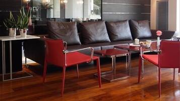 Een moderne woonkamer met een donker leren bank, rode stoelen en een houten salontafel.