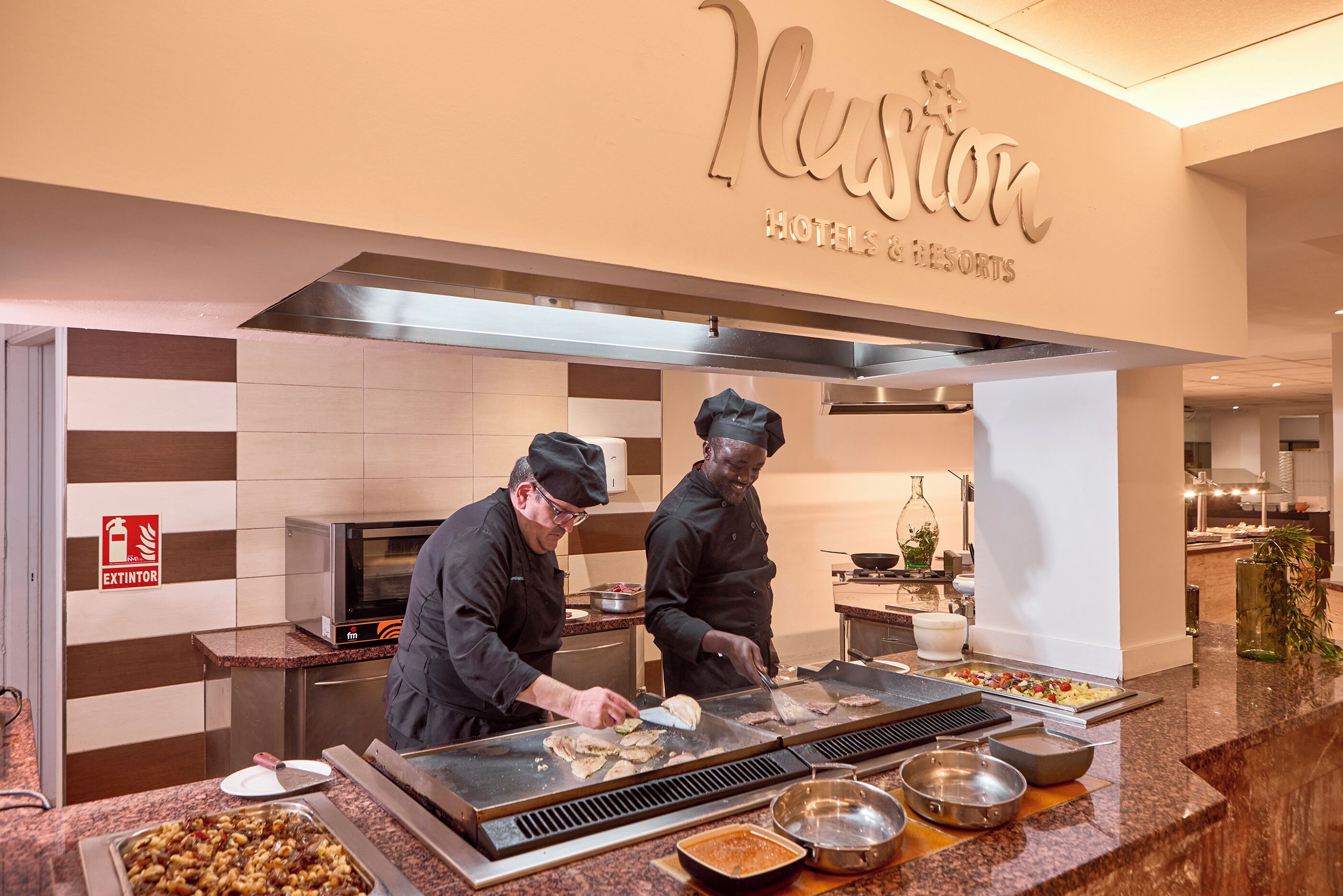 A kitchen area with chefs preparing food at a buffet counter.