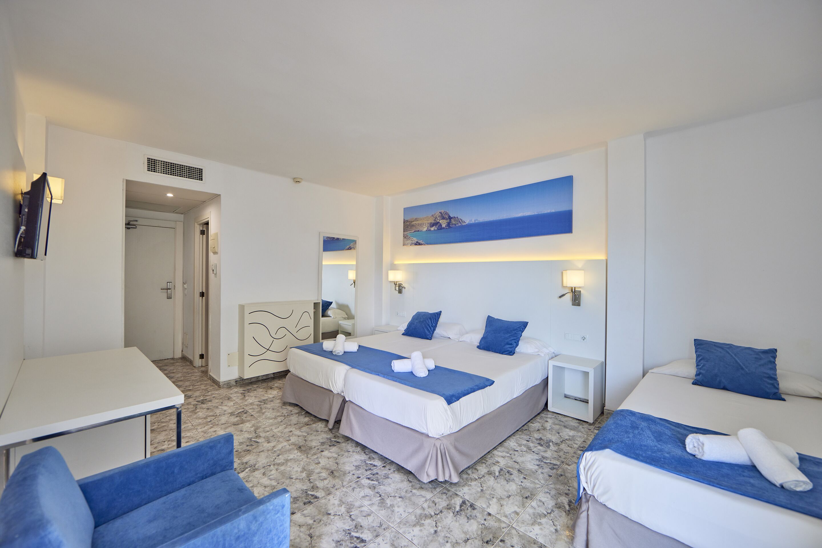 Una habitación de hotel con dos camas, un escritorio, una silla y un baño.