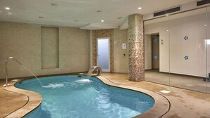 An indoor swimming pool with a water feature, tiled walls, and a glass partition. - Hotel Ilusion Calma & Spa (Palma de Mallorca)