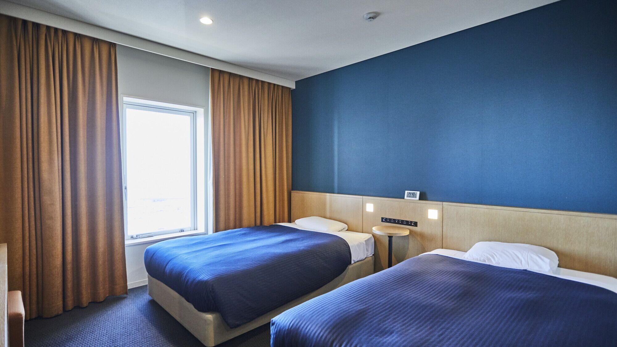 Une chambre d’hôtel avec deux lits, une fenêtre et une horloge murale.
