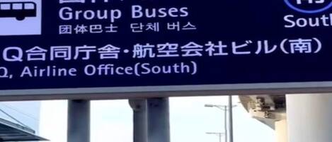 A sign with directions to Group Buses, Airline Office, and Q, with Japanese text.