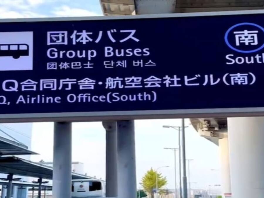 A sign with directions to Group Buses, Airline Office, and Q, with Japanese text.