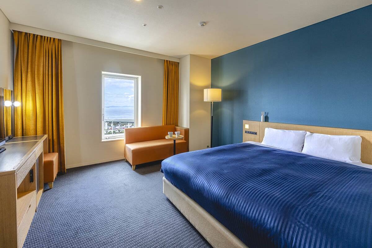 Een hotelkamer met een groot bed, een bureau, een stoel en een raam met gordijnen.