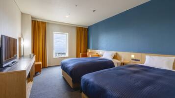 A hotel room with two beds, a desk, a TV, and a window with curtains.