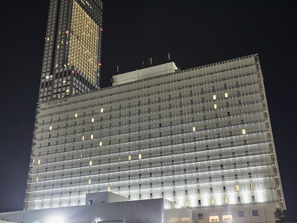 Un edificio alto con fachada de diseño enrejado, varios pisos y ventanas uniformemente distribuidas.