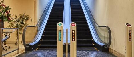 An indoor escalator with a "No Entry" sign and an "Automatic Operating" sign.