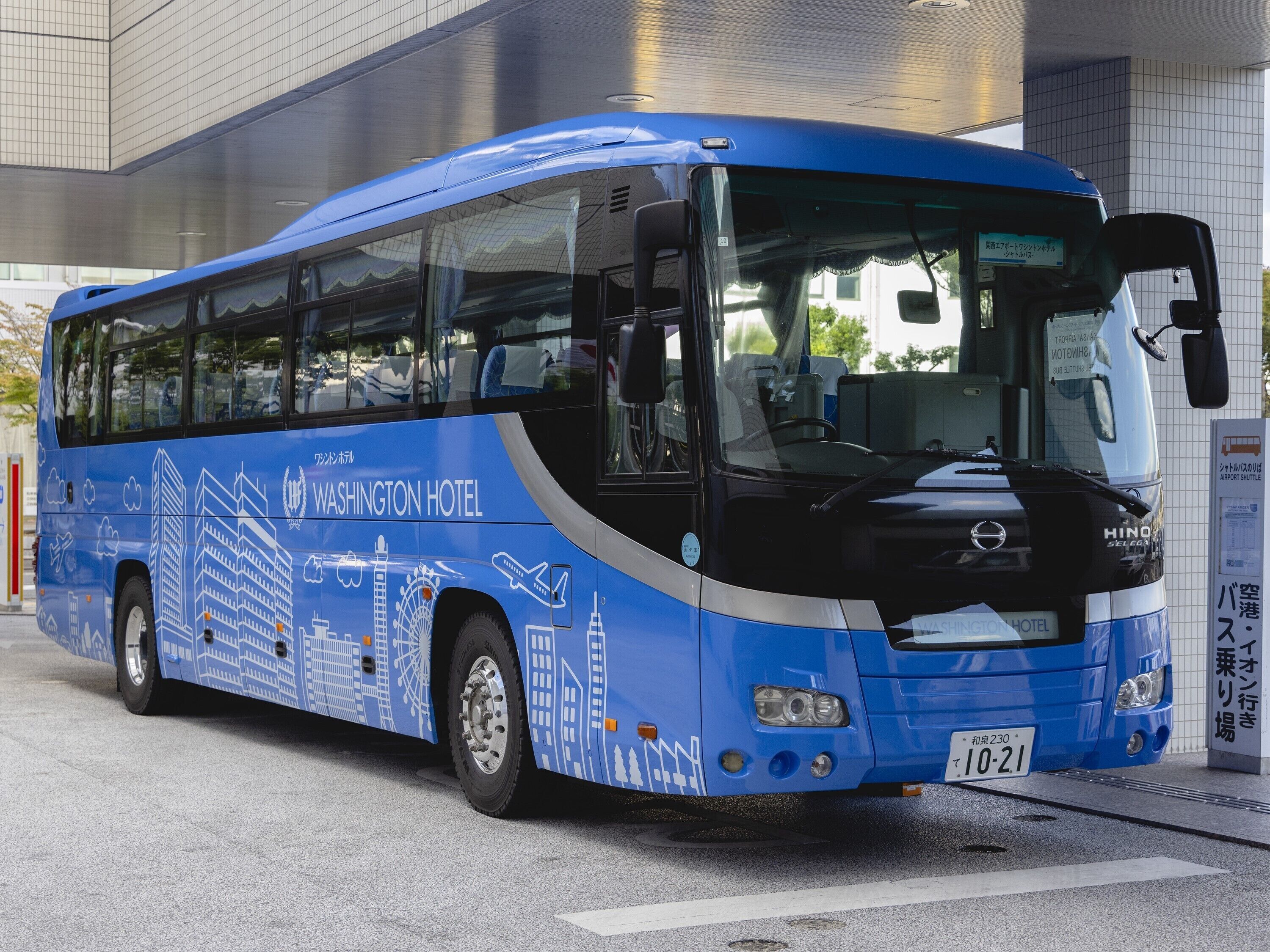 A blue bus with "Washington Hotel" branding, parked at a bus stop.