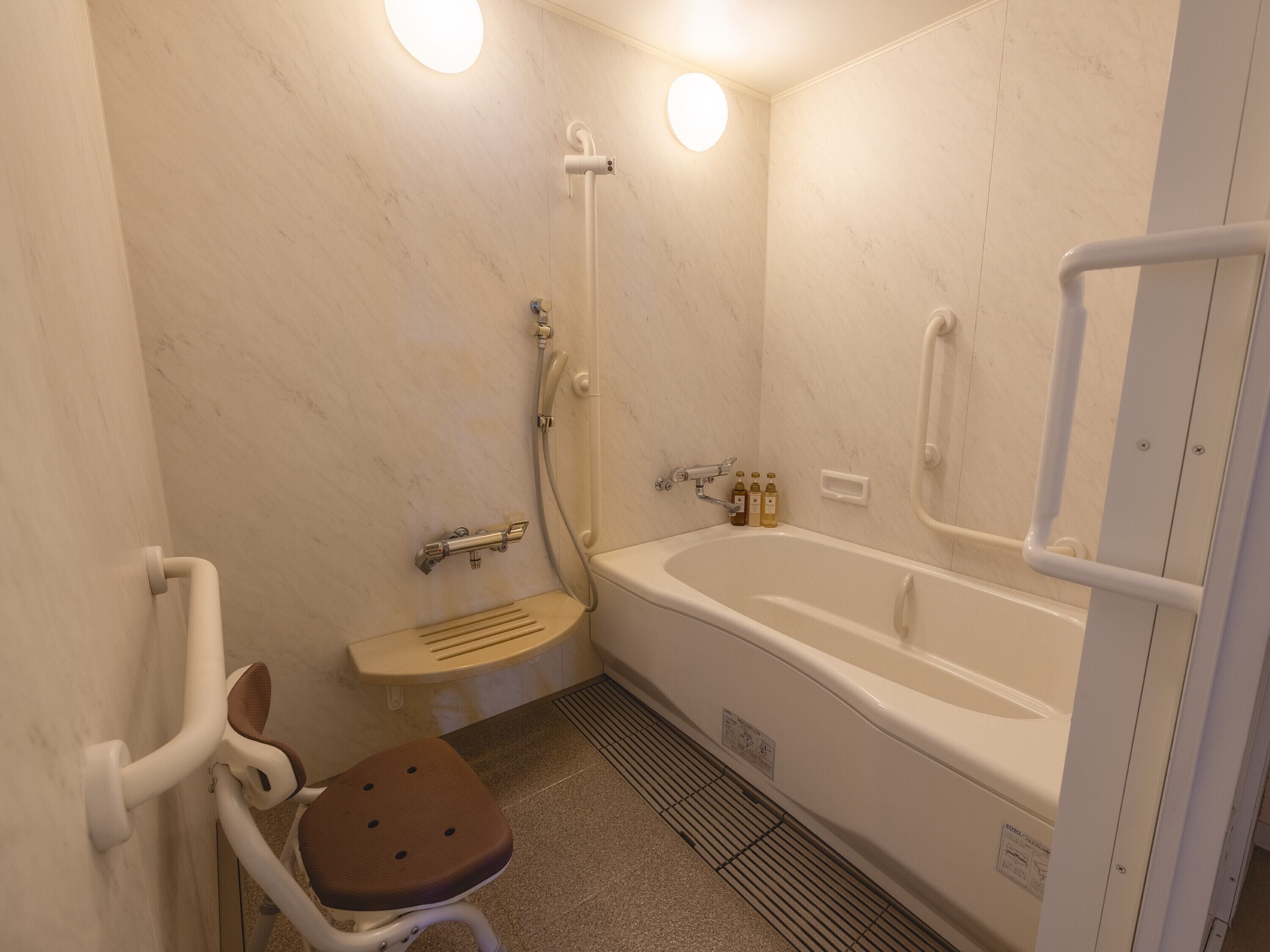 A bathroom with a bathtub, a shower, a toilet, and a handrail.