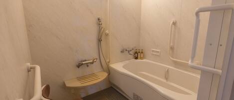A bathroom with a bathtub, a shower, a toilet, and a handrail.