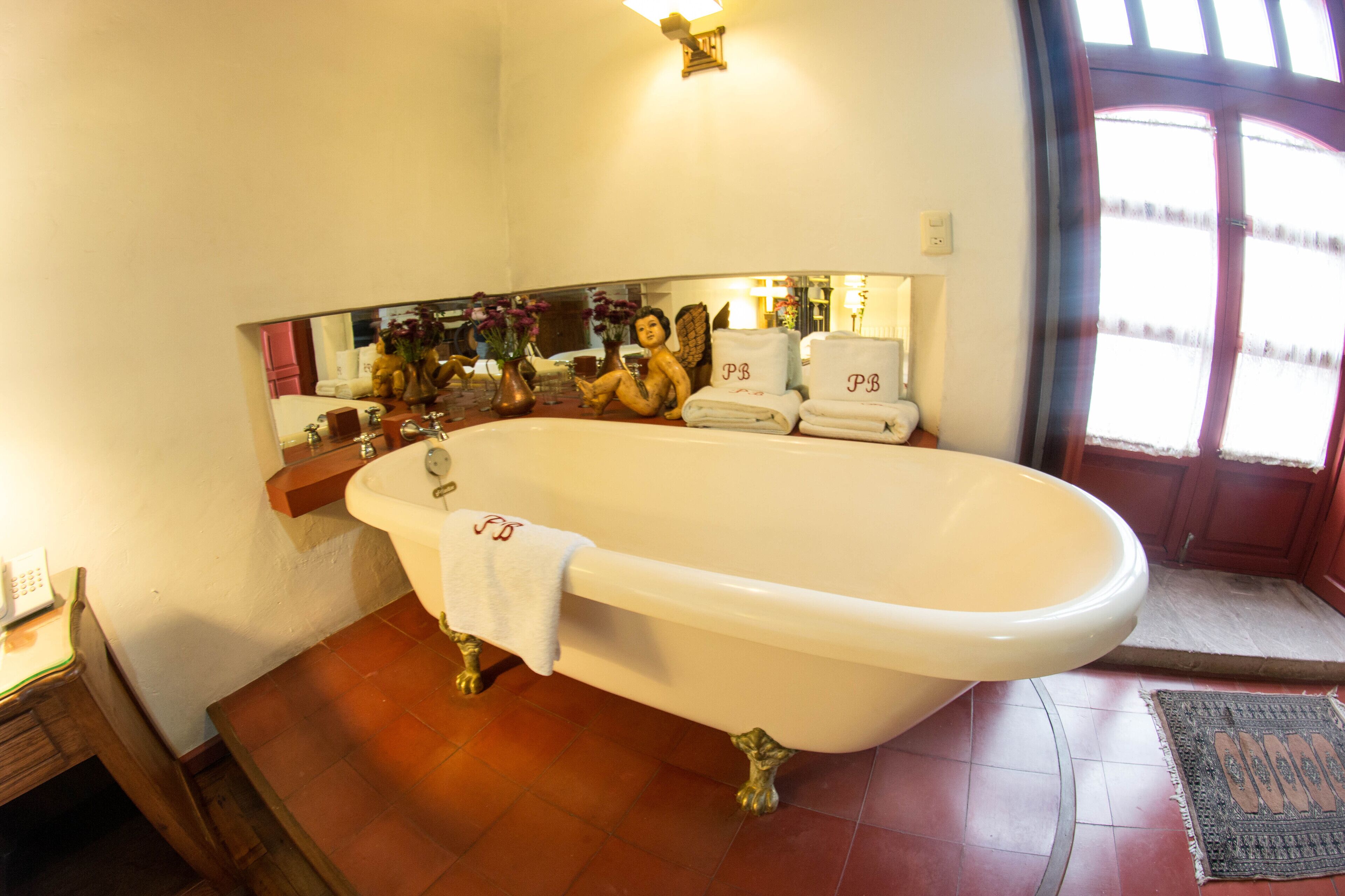 A bathroom with a freestanding bathtub, a vanity with a mirror, and a towel rack with towels.