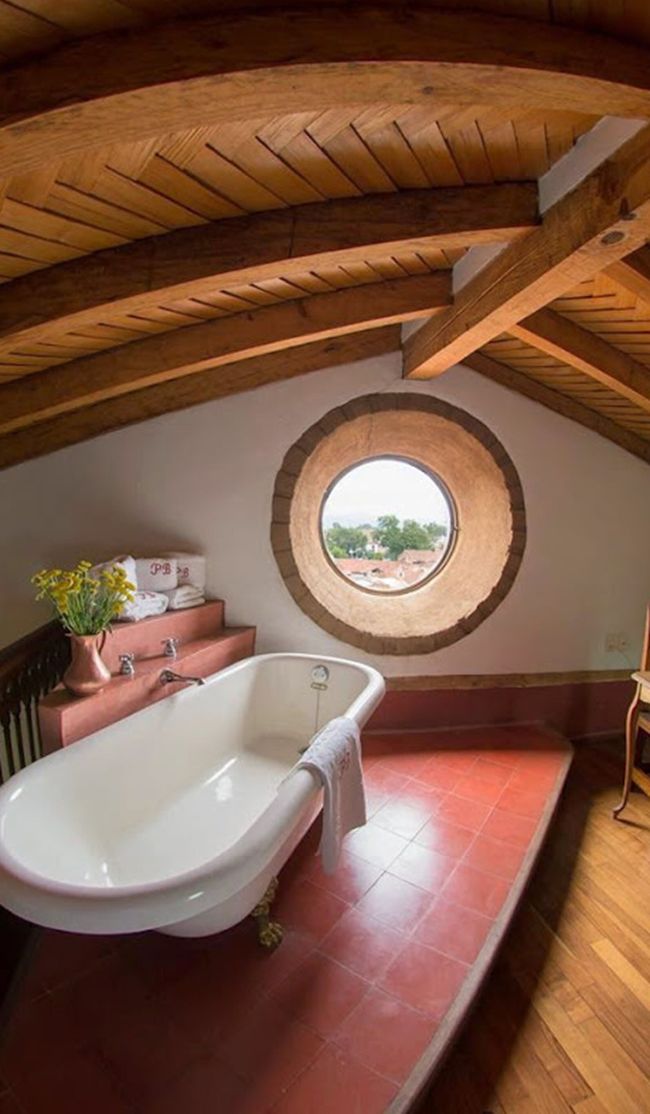 Un baño con una bañera independiente, una ventana con vistas y un techo de madera.
