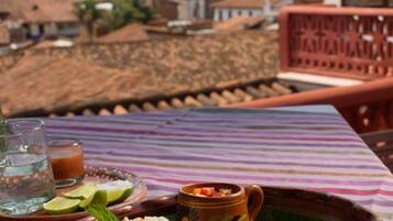 Una mesa con comida que incluye arroz, pescado frito y una ensalada, frente a un paisaje urbano.