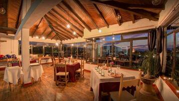 Un restaurante con vigas de madera, ventanas amplias y mesas dispuestas para comer.