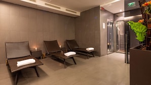 Een wellnessruimte met drie ligstoelen, een tafeltje en een groene plant.