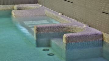 A swimming pool with a tiled edge and steps leading into the water.