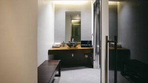 Een moderne badkamer met een houten wastafelmeubel, een glazen wastafel en een spiegel.