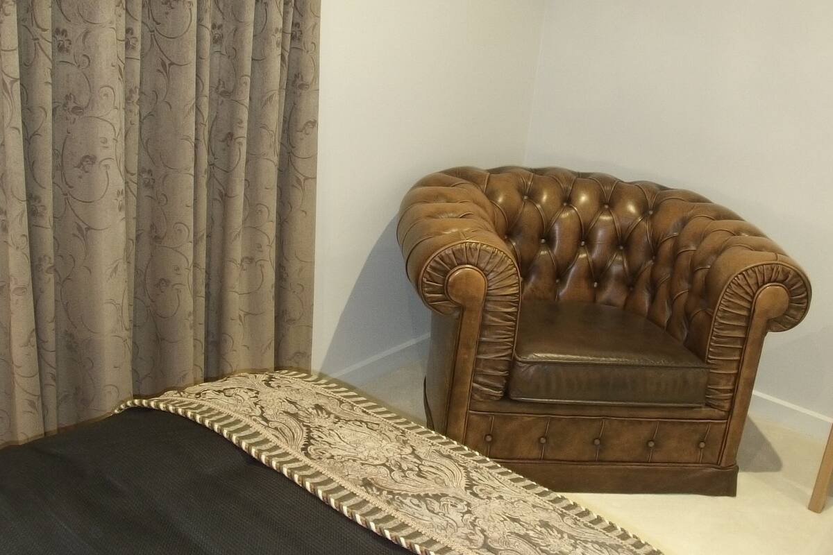 A room with a brown leather armchair, a patterned throw, and a curtain with a floral design.