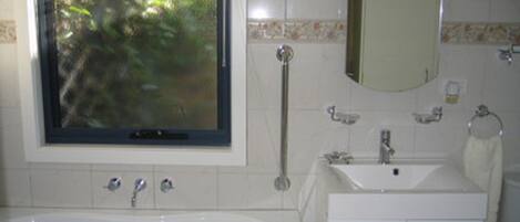 A bathroom with a bathtub, a sink, a mirror, and a window.