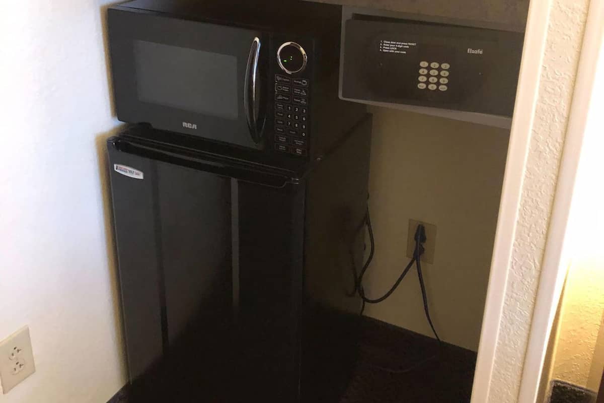 A compact kitchenette with a refrigerator, microwave, and a small coffee maker on the countertop.