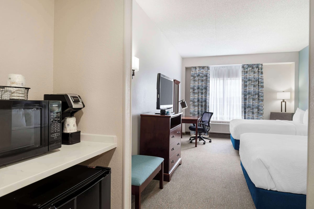 A hotel room with a bed, a desk with a computer, a microwave, and a coffee maker.