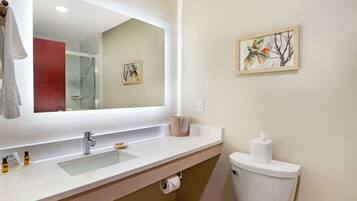Une salle de bain avec un lavabo blanc, un miroir, des toilettes et un tableau encadré au mur.