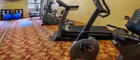 A gym with treadmills, stationary bikes, and exercise balls.
