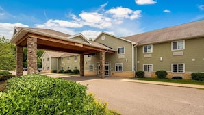 A multi-story hotel with a covered entrance, stone pillars, and a landscaped driveway. - Crandon Inn and Suites (Crandon)