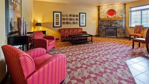 A living room with a fireplace, a sofa, and two armchairs. - Crandon Inn and Suites (Crandon)