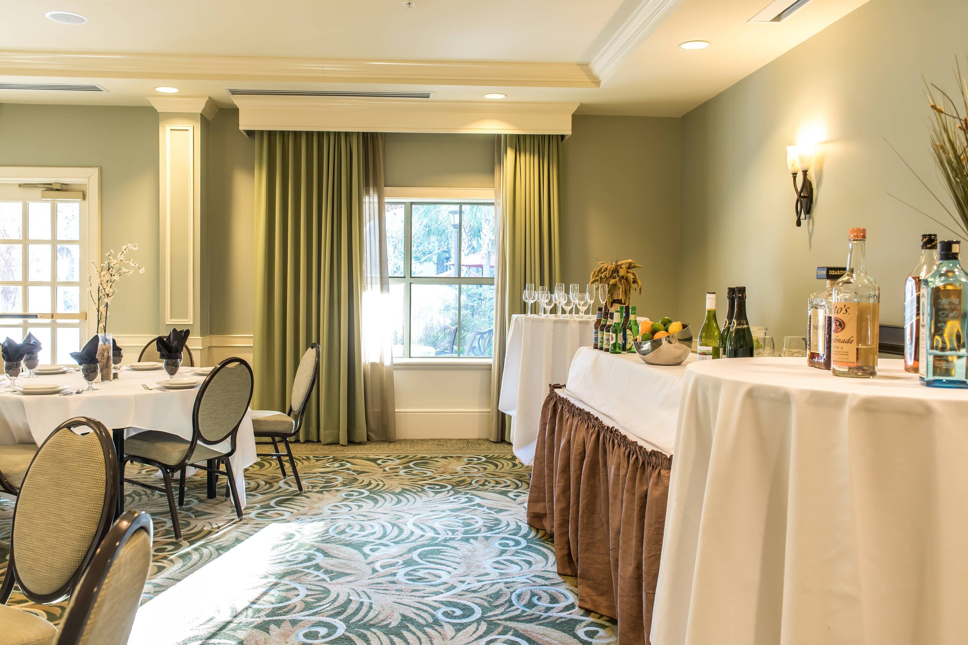 A dining area with a table set for a meal, a bar area with bottles, and a window with curtains.