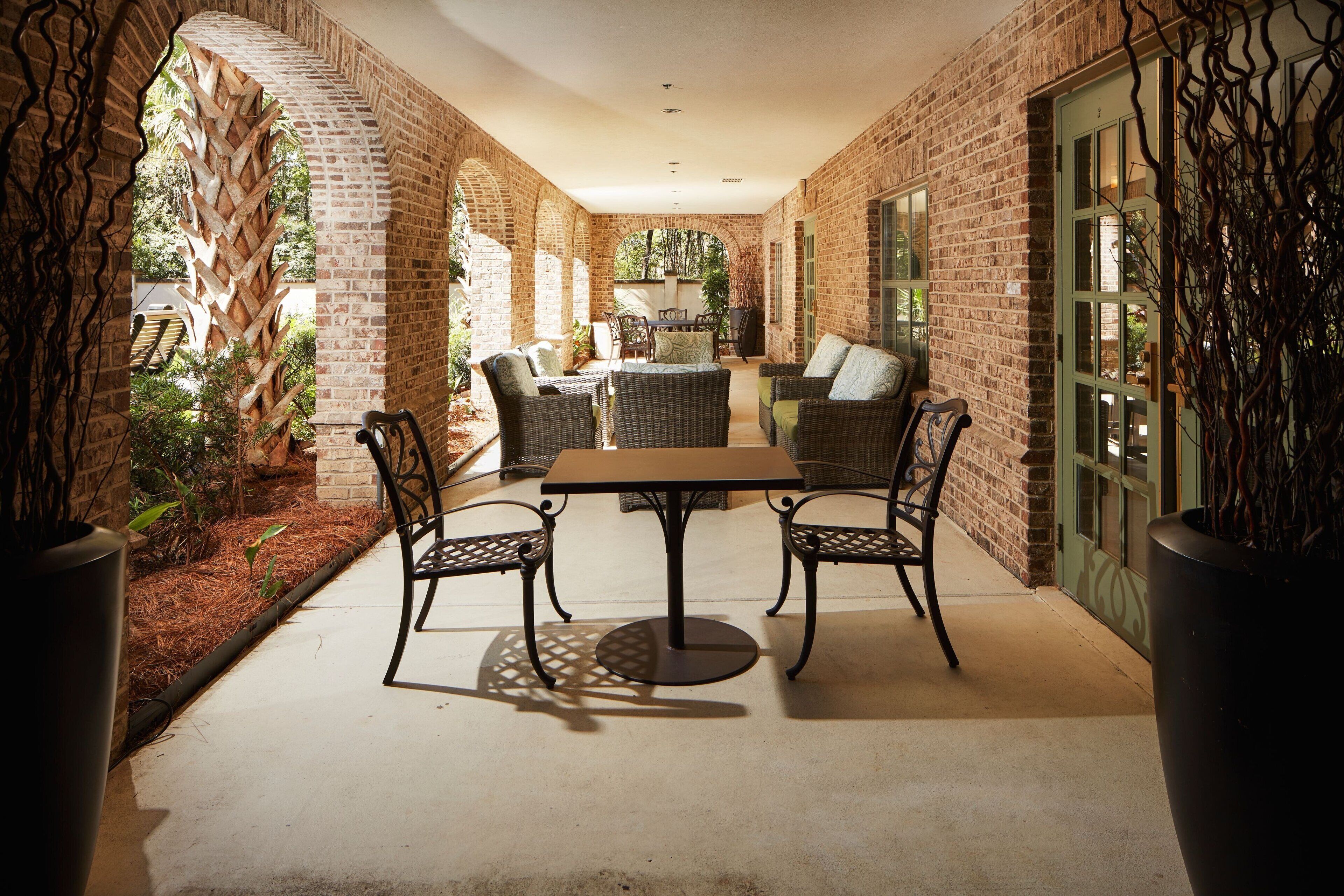 An enclosed patio area with brick walls, a table, and wicker chairs.