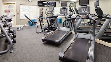 A gym with treadmills, dumbbells, and exercise equipment.